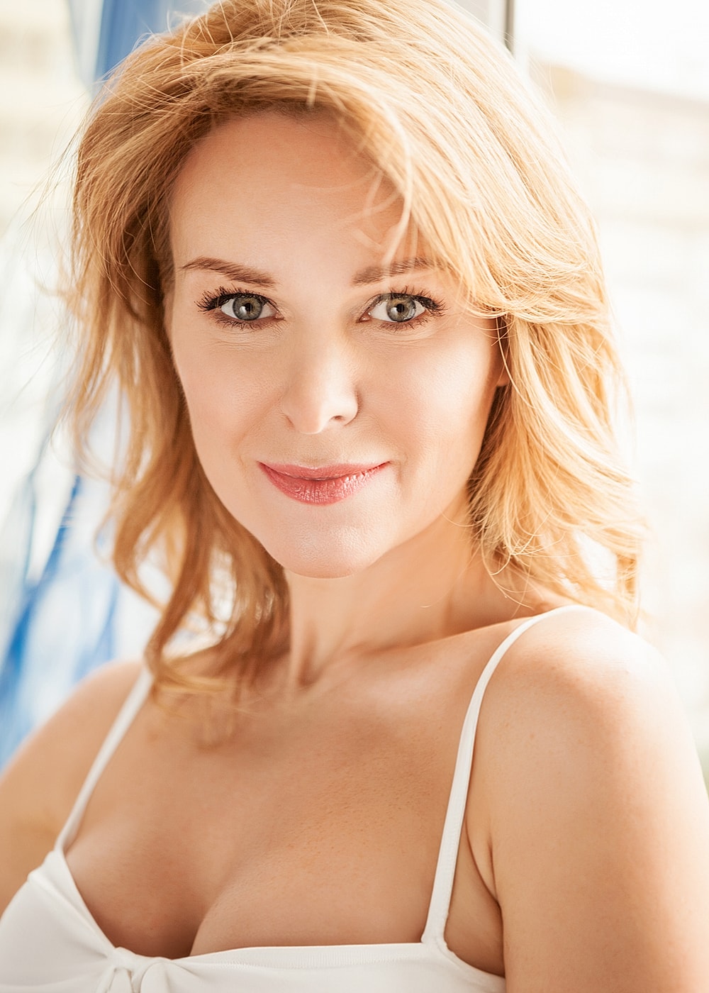 Smiling woman with blonde hair and soft lighting.