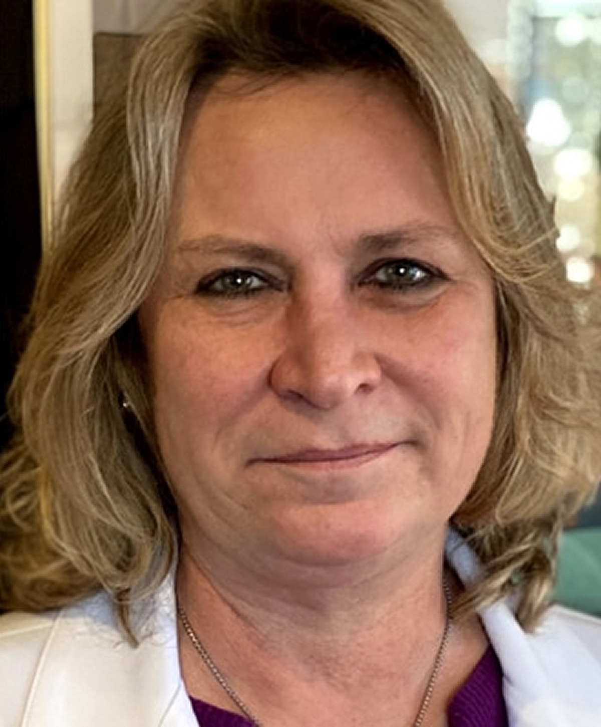 Woman with blonde hair and white jacket.
