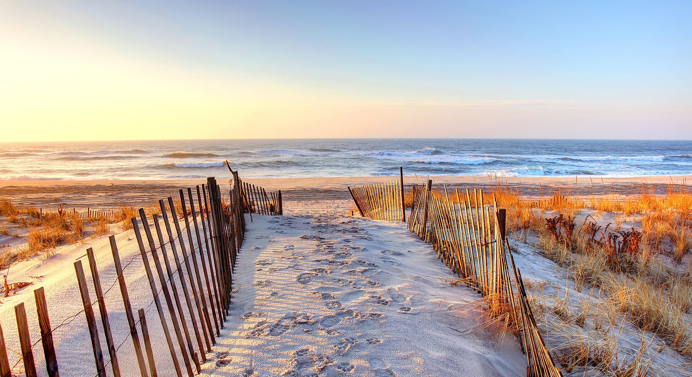 Beach pathway with sunset and ocean view.
