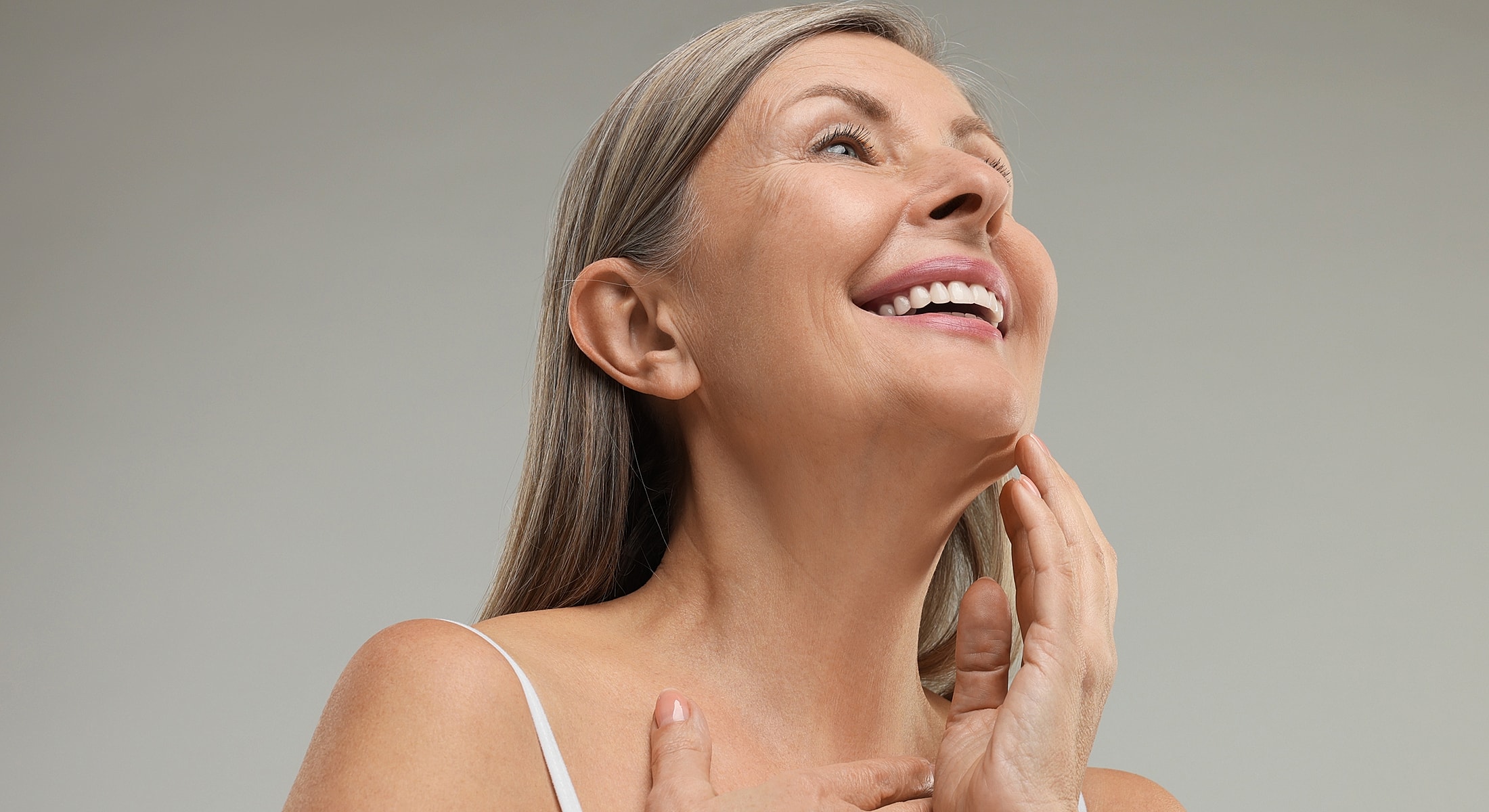 Smiling mature woman with long hair touching chin.