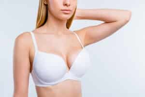 A woman in a white bra after a successful breast augmentation recovery